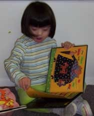 A young girl engrossed in a book while sitting on the floor.